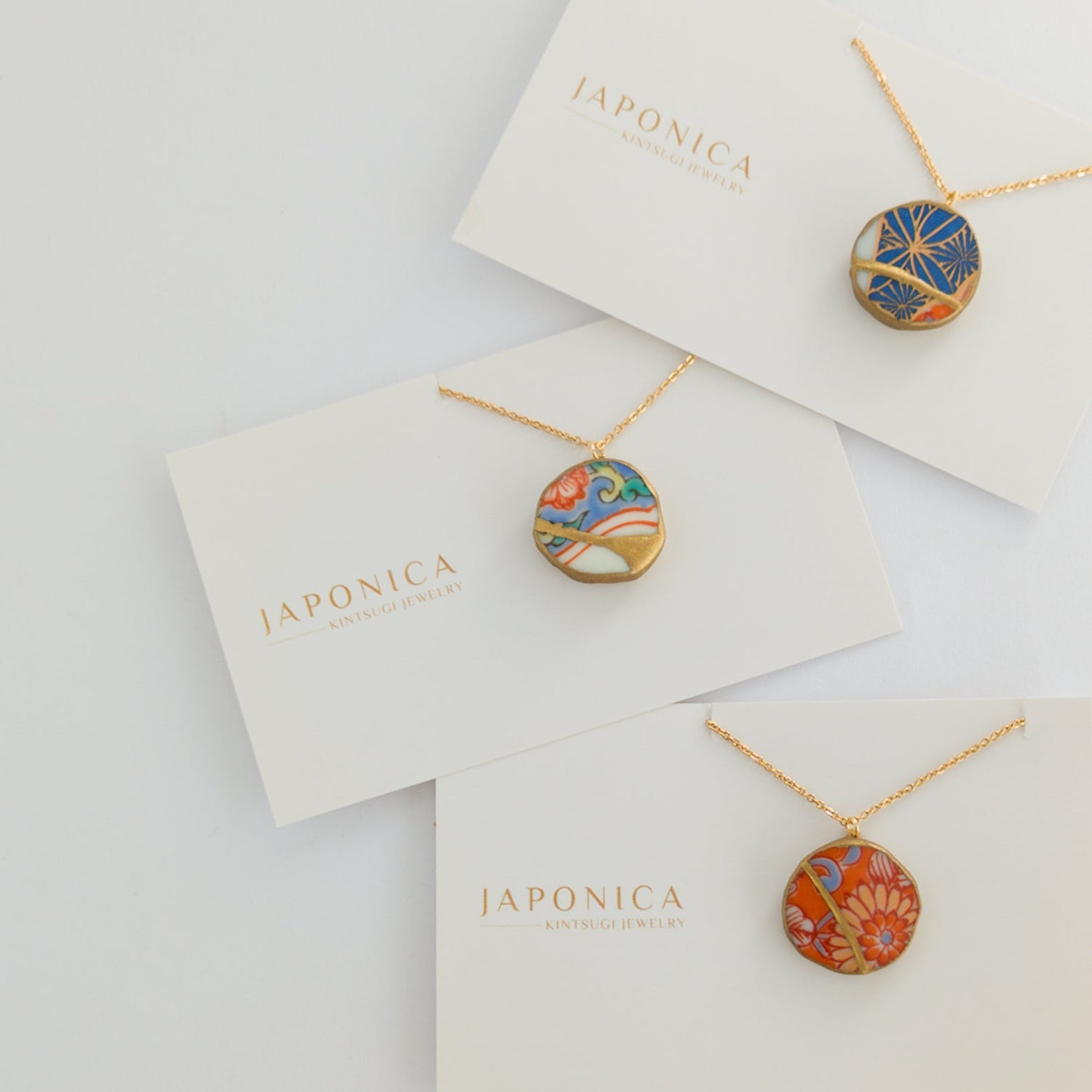 Japonica necklaces on display with branded cards on a light gray background
